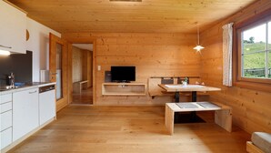 Een houten interieur met een keuken, een eethoek en een televisie.