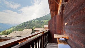Een houten balkon met uitzicht op een bergachtig landschap.