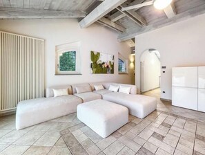 A modern living room with a sectional sofa, a radiator, and artwork on the walls. - Hostdomus - King Suite (Marina di Andora)