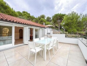 A patio with a glass table and chairs, a red-tiled roof, and a view of trees. - Hostdomus - King Suite (Marina di Andora)
