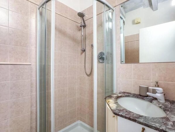 A bathroom with a glass shower enclosure, a marble sink, and a mirror. - Hostdomus - King Suite (Marina di Andora)