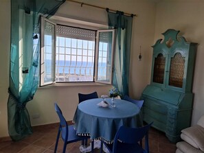 A room with a dining table, chairs, a cabinet, and a window with a view. - Gorgeous beachfront villa, 1 hour away from Rome, parking spaces included. (Anzio)
