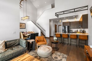 Eine moderne Küche mit Barhocker, ein Essbereich mit Tisch und Stühlen sowie eine Treppe zu einer weiteren Ebene.