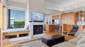 Een moderne woonkamer met een open haard, zithoek, keuken en eethoek.