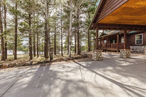 Eine Lodge mit überdachter Veranda, Steinpfeilern und Blick auf ein bewaldetes Gebiet.