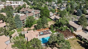 An aerial view of a residential area with houses, a swimming pool, and a wooded area.