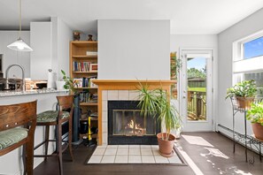 A modern kitchen with a fireplace, wooden chairs, a bookshelf, and a potted plant. - New! Boulder Retreat | Pool | Hot Tub | Gym | Explore the City and Mountains (Boulder)