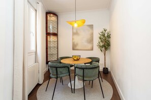 A dining area with a round table, four chairs, a hanging light fixture, a potted plant, and a large abstract painting on the wall. - Discover this sophisticated apartment located on Calle Alonso Cano, in the heart of the Salamanca district, one of Madrid's most exclusive and well-connected areas. (MADRID)