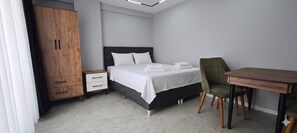 A hotel room with a bed, a desk, a chair, a wardrobe, and a nightstand. - Doğuş Apart (Antalya)
