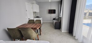 A modern hotel room with a dining area, kitchenette, sofa, and a TV. - Doğuş Apart (Antalya)
