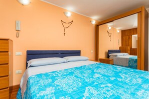 Ein Schlafzimmer mit einem Bett, einem Holzschrank und einem Spiegel.