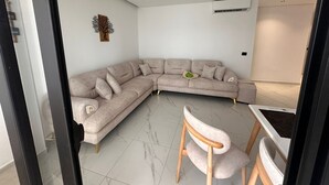 A modern living room with a L-shaped sectional sofa, a wooden chair, and a small dining table.
