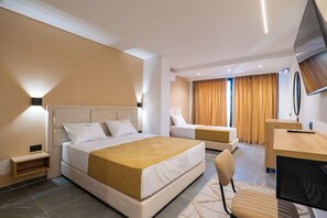 Habitación de hotel con dos camas, un escritorio, una silla, un televisor y una ventana con cortinas.