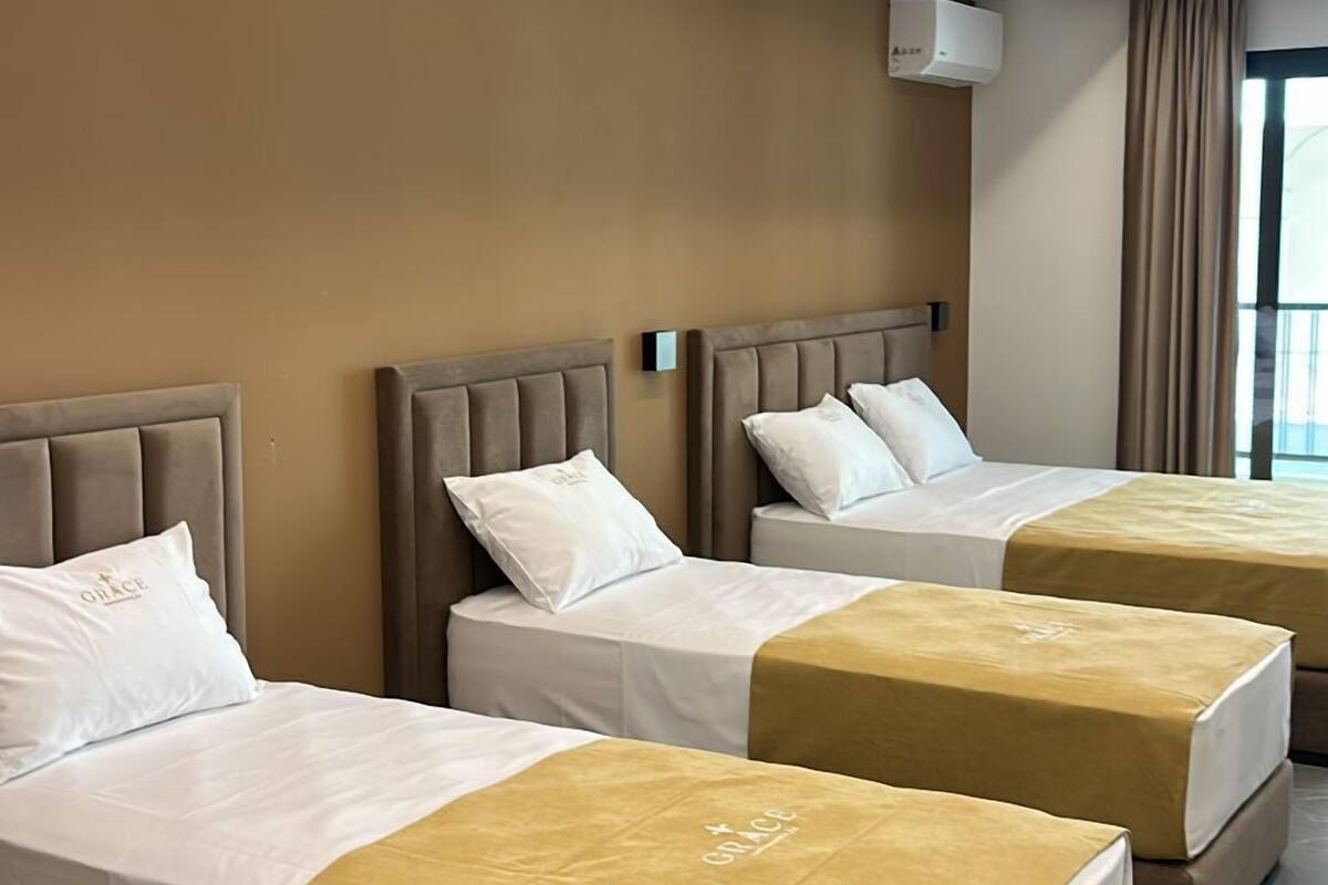 A hotel room with three beds, a modern design, and a large window.