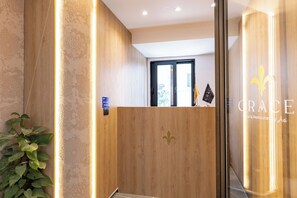 Un área de recepción con un mostrador de madera, una planta y una ventana con vistas.