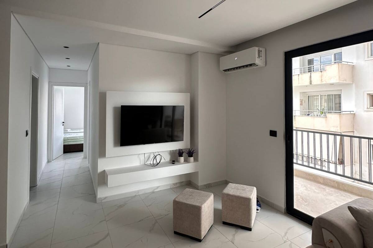 A modern living room with a flat-screen TV, a sofa, and a balcony.