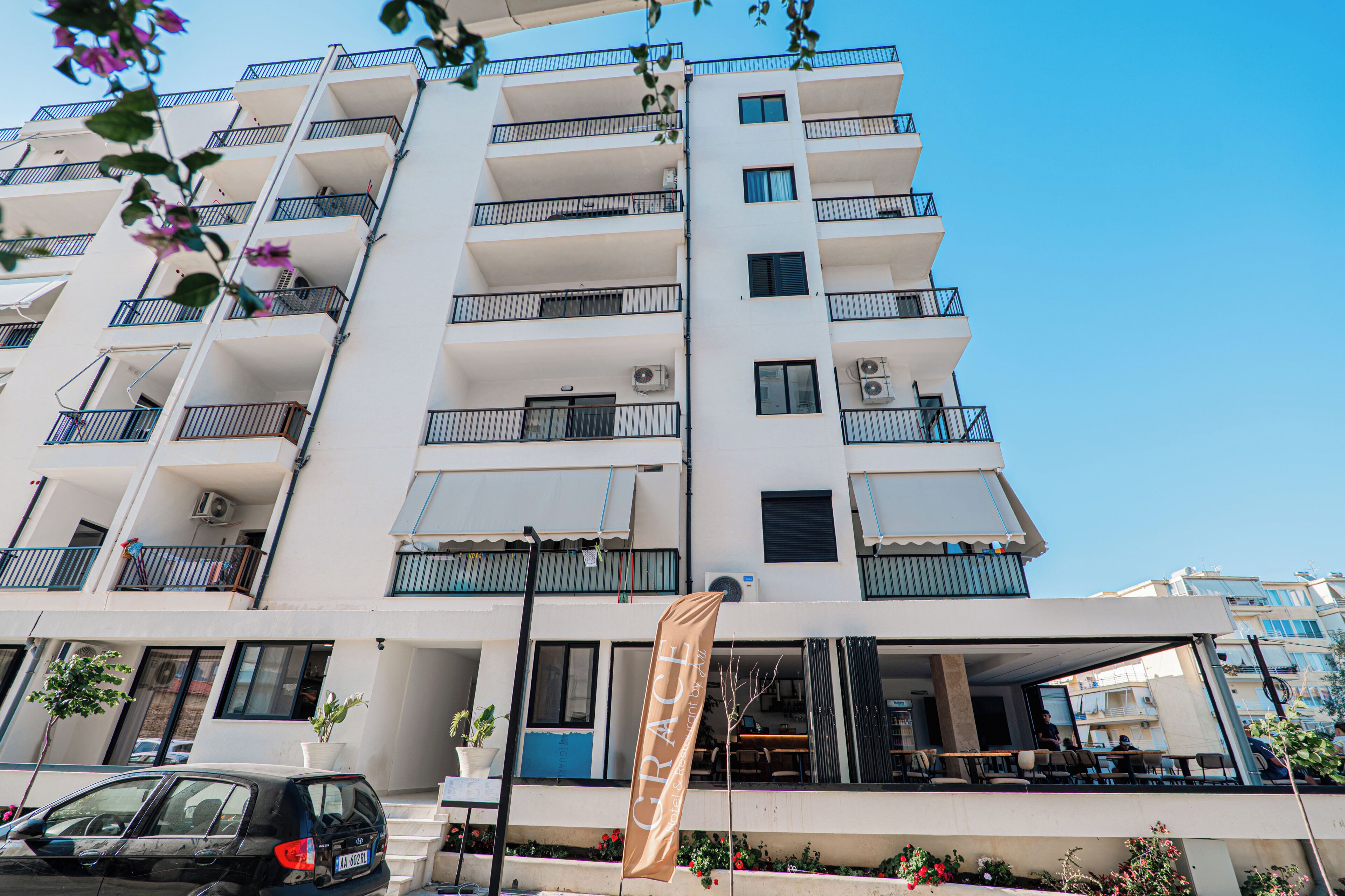 Een hotel met meerdere verdiepingen, balkons, een overdekt terras en een vlag.