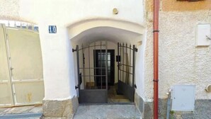 A gated entrance with a metal gate, a stone archway, and a small door. - Hostdomus - The house between olive trees and history (Toirano)