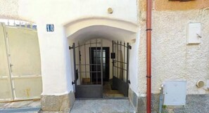 Une entrée fermée par un portail en métal, un arc en pierre et une petite porte.