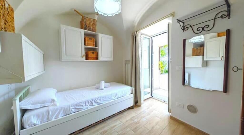 Une chambre à coucher avec un lit, des armoires blanches et un miroir.