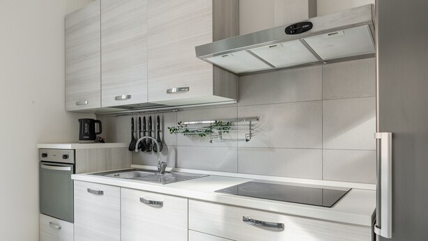 A modern kitchen with white cabinetry, a stainless steel range hood, and a built-in oven. - Mascarella Cozy Studio by Wonderful Italy (Bologna)