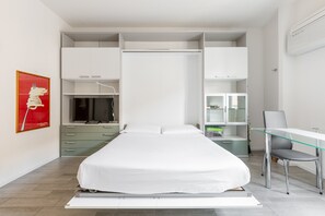 Ein modernes Schlafzimmer mit Bett, Schreibtisch und integrierten Stauraumlösungen.