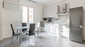 A modern kitchen with a glass dining table, stainless steel appliances, and a view of the city. - Mascarella Cozy Studio by Wonderful Italy (Bologna)