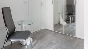 A modern room with a glass table, a black chair, and a mirrored wardrobe. - Mascarella Cozy Studio by Wonderful Italy (Bologna)