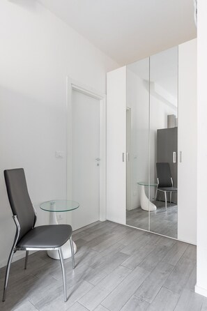 Ein modernes Zimmer mit Glastisch, schwarzem Stuhl und einem Schrank mit Spiegel.