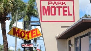 Placa de motel com a inscrição 'PARK MOTEL' e um aviso de 'Vagas' abaixo.