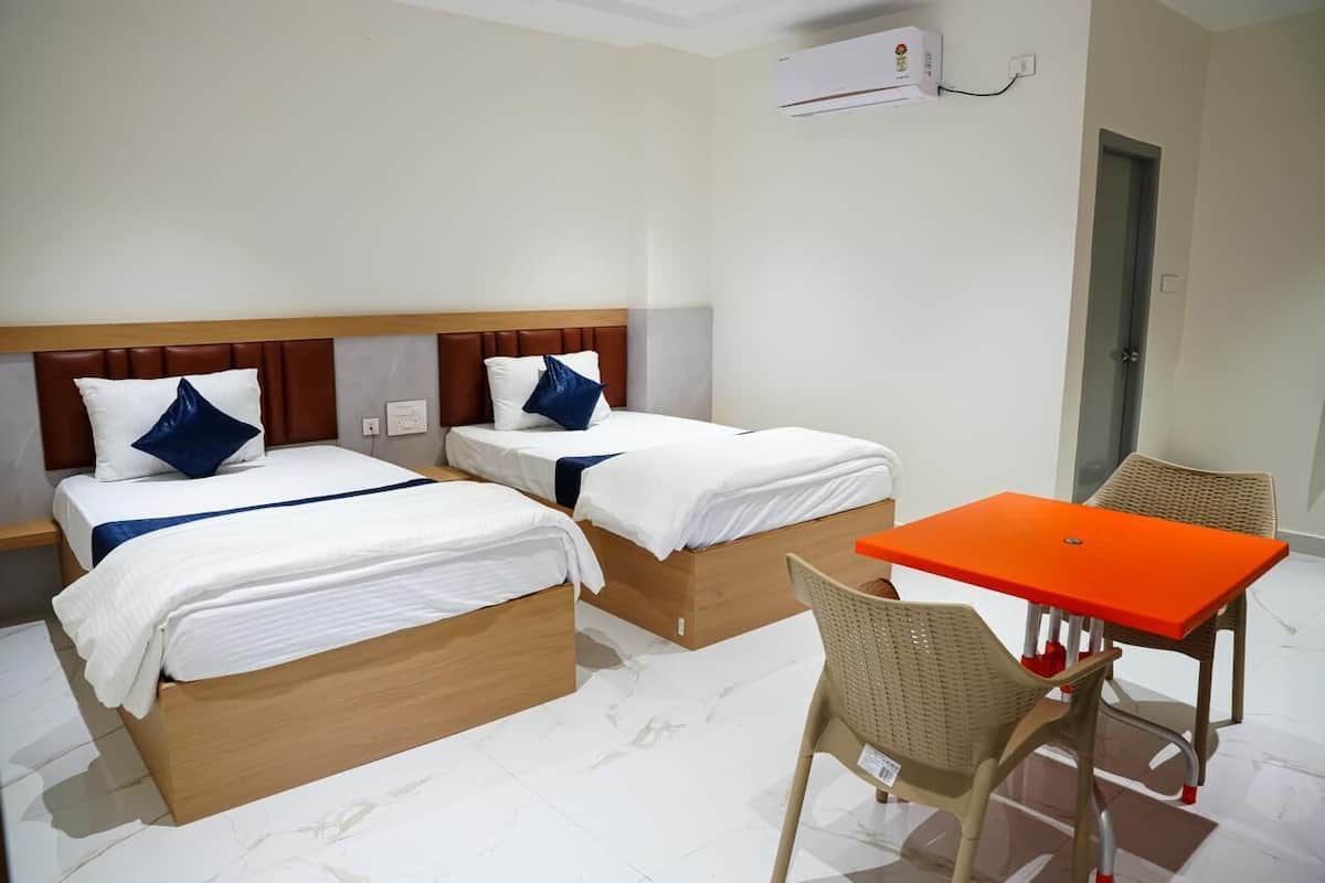 A hotel room with two beds, a small table, and two chairs.