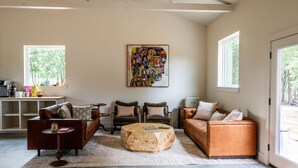 A spacious living room with a coffee table, sofas, and a large abstract painting on the wall.