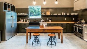 A modern kitchen with a central island, bar stools, and a large window.