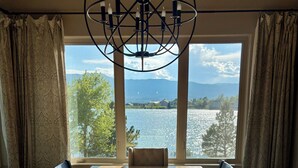A dining area with a large wooden table, black chairs, a central bowl, and a chandelier. - Spacious 4-bedroom ranch-style home 10 min from USAFA with lake & mountain views (Monument)