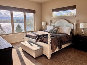 Ein Schlafzimmer mit einem großen Bett, zwei Nachttischen, einer Bank und Seeblick.