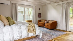 A bedroom with a bed, a guitar, a suitcase, and a sofa. - Cozy & Family-Friendly Lake Oasis: Ofuro Tub, King Bed, Bunks & Workspace! (Jewett)