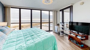 Une chambre dotée d’un grand lit, d’une télévision et offrant une vue sur la plage.
