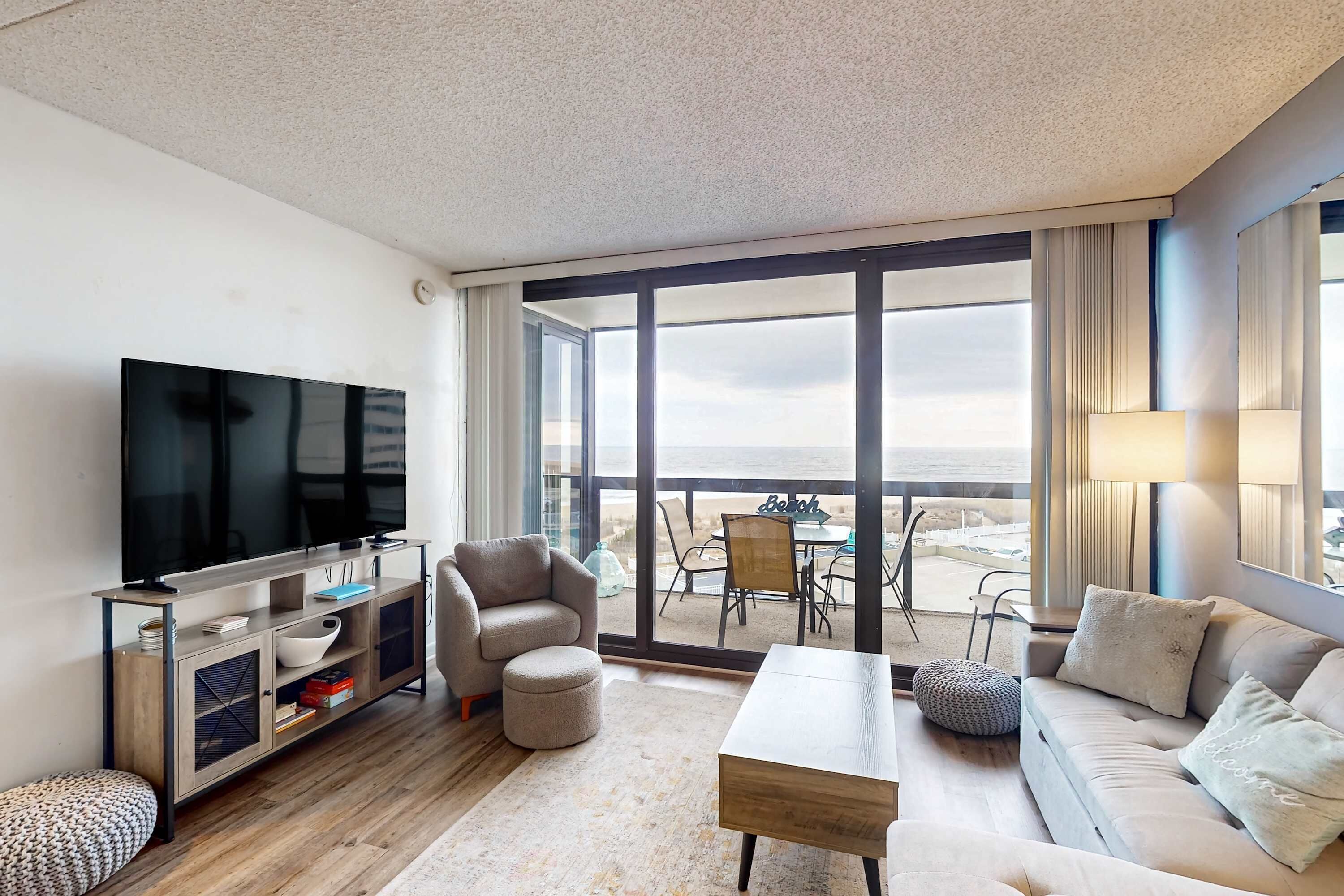 Een moderne woonkamer met een flatscreen televisie, een bank, een salontafel en een balkon met uitzicht.