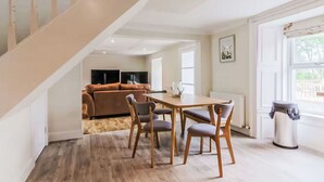 Een moderne woonkamer met een eetgedeelte, een trap en uitzicht op de omgeving.