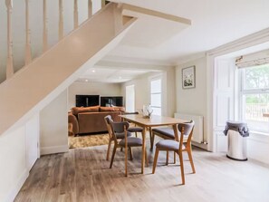 Ein modernes Wohnzimmer mit Essbereich, einer Treppe und Blick ins Freie.