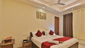 A hotel room with a large bed, a nightstand, a ceiling fan, and a window with curtains. - HOTEL O BLUE DIAMOND (Lucknow)