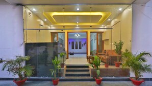 A modern building entrance with glass doors, potted plants, a staircase, and a seating area. - HOTEL O BLUE DIAMOND (Lucknow)