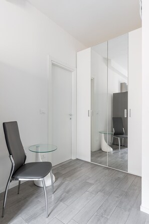 Ein modernes Zimmer mit einem Glastisch, einem Sessel und einem Schrank mit Spiegel.