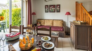 A dining area with a table set for two, a sofa, and a staircase. - Duplex Maisonette in the Heart of Dordogne (Bergerac)