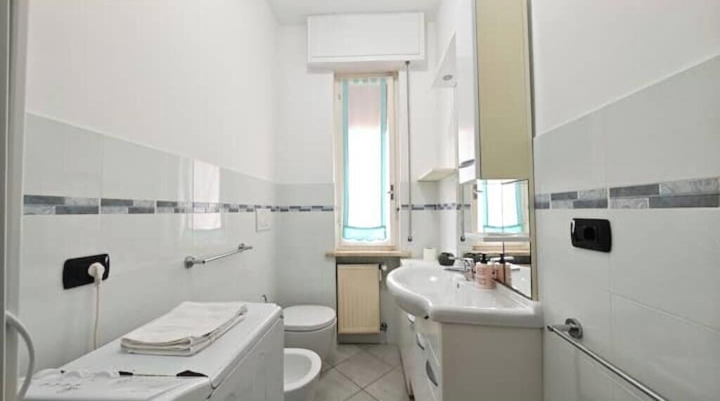 A compact bathroom with a toilet, sink, and mirror.