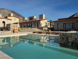 Zona de piscina con vistas despejadas, paredes de piedra y montañas al fondo.