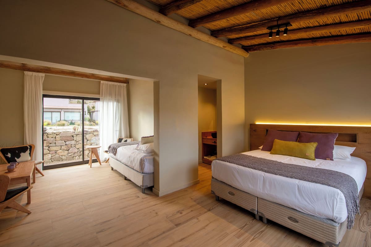 Un dormitorio con una cama grande, un escritorio y vistas a través de un ventanal.