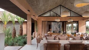 Un espacio moderno para comer al aire libre con muebles de mimbre, ventanas amplias y vistas al jardín.