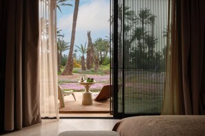 Ein Zimmer mit einer großen Schiebeglasdoor zum Garten mit Palmen und Blumen.