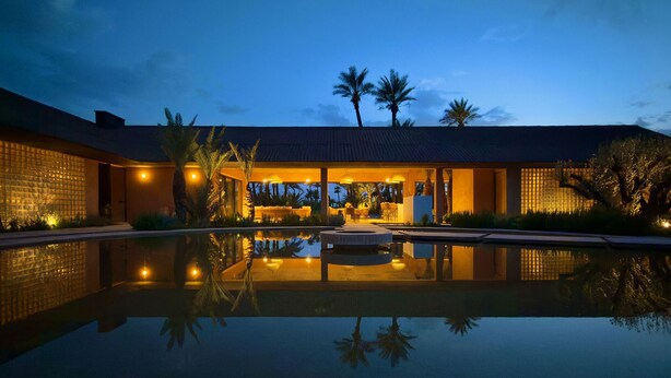 Un resort moderno con piscina, palmeras y una zona de estar al aire libre bien iluminada.